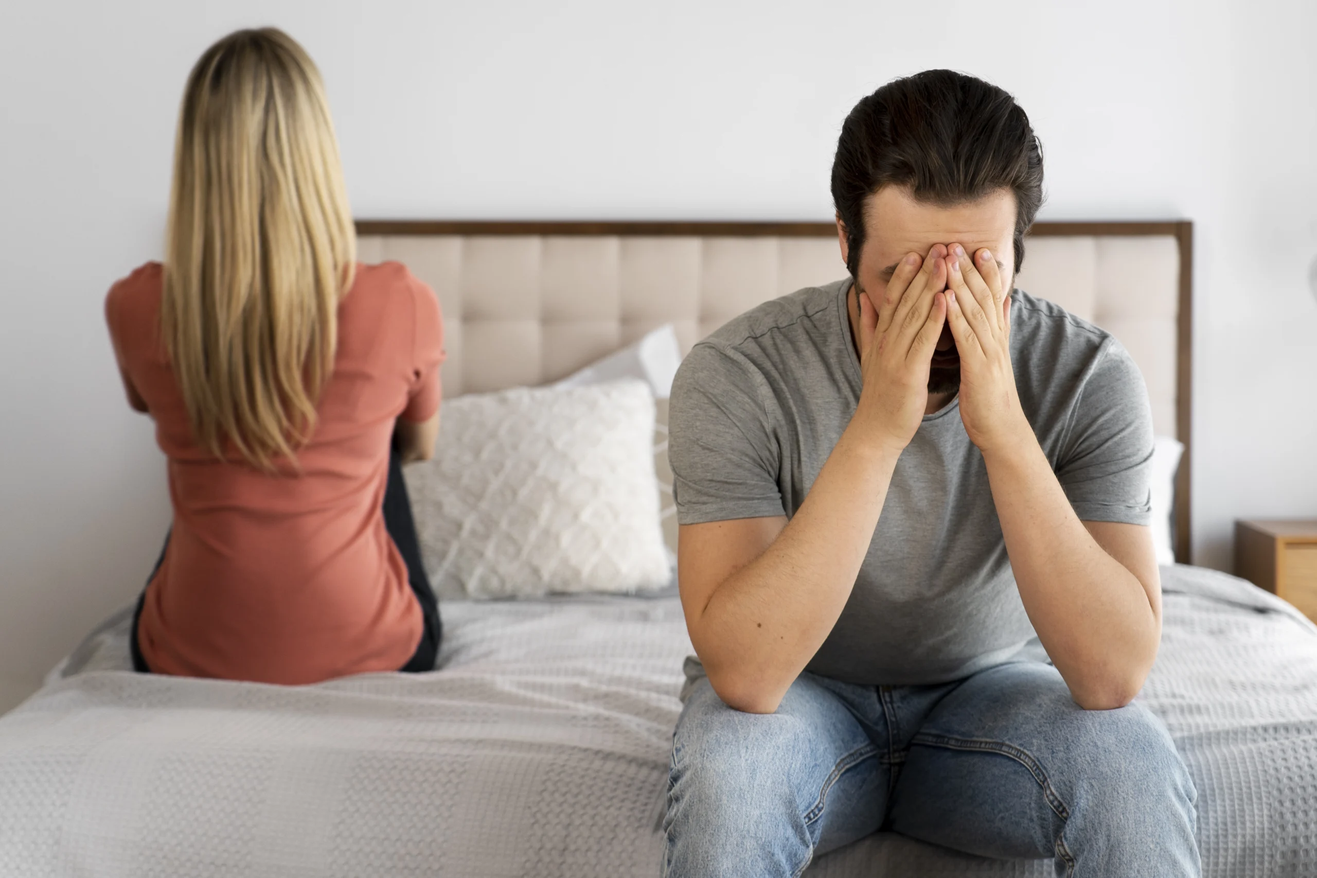 Couple assis à distance sur un canapé, une femme réfléchit au reproche formulé par son mari.