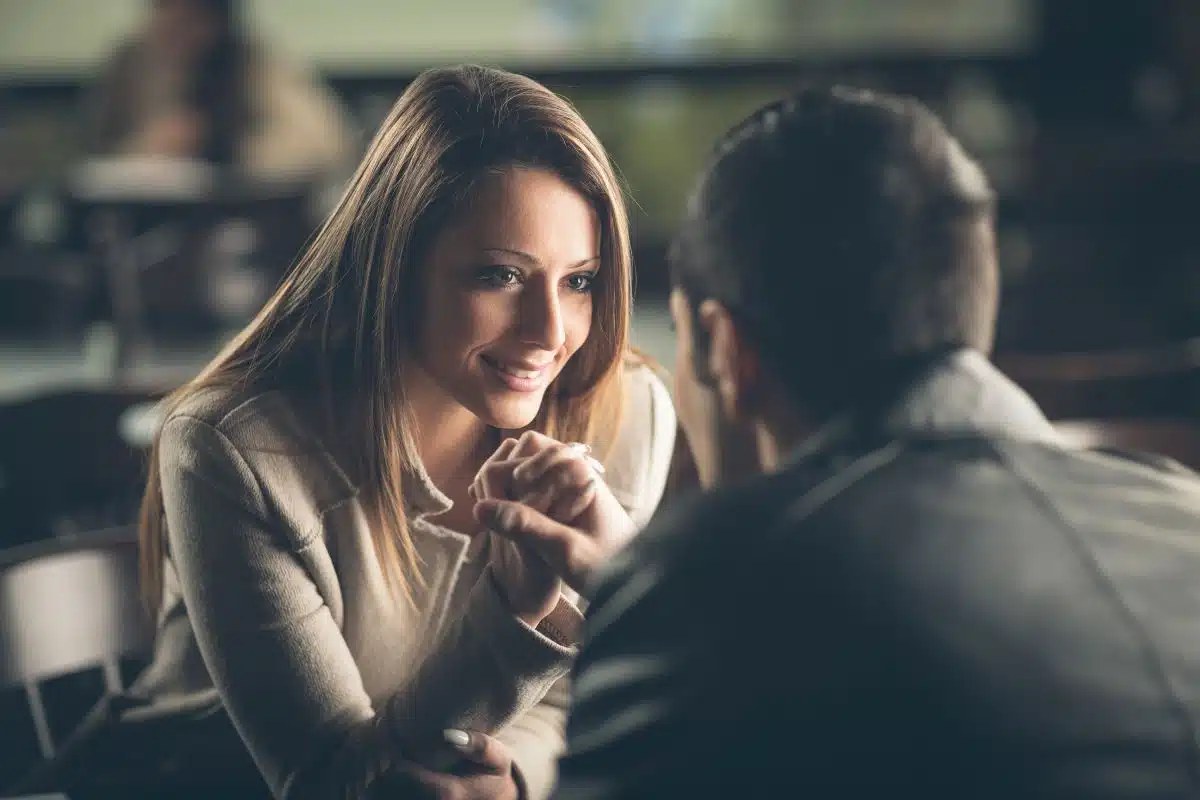 Homme assis face à une femme, buste orienté vers elle et regard posé sur elle pendant une conversation